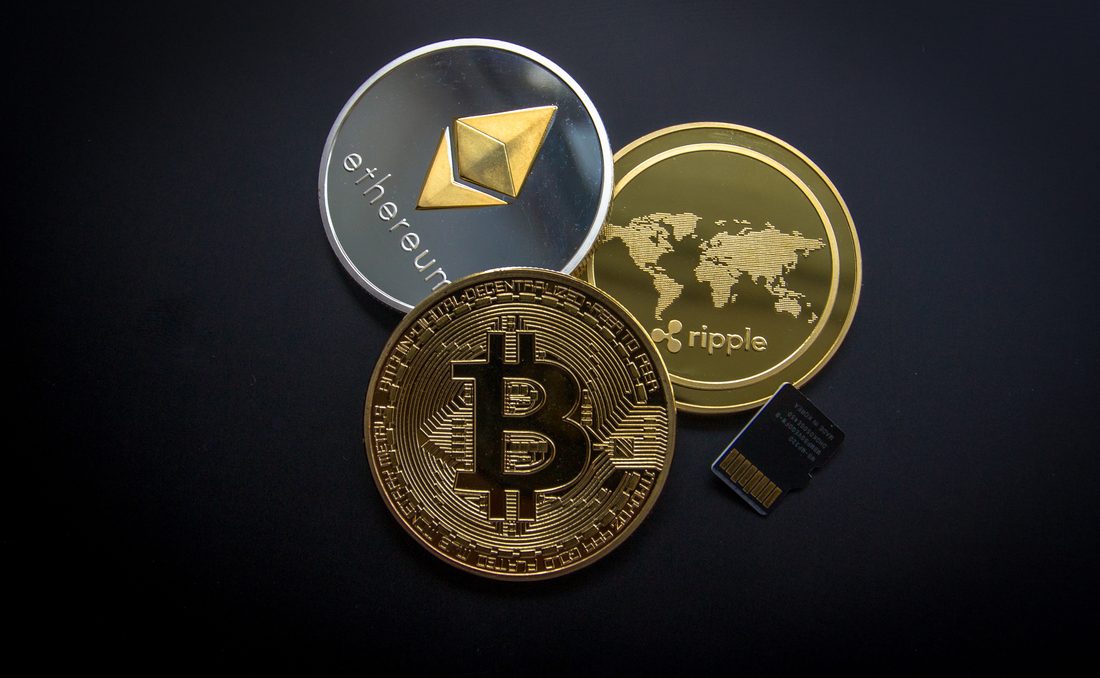 Ethereum, Bitcoin and Ripple coins on a dark world map